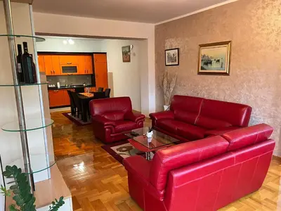 a living room with red leather furniture and a kitchen at Apartman Sudnica Banja Luka in Banja Luka