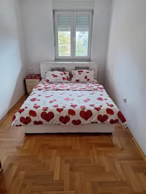 a bedroom with a bed with red flowers on it at Apartman Sudnica Banja Luka in Banja Luka