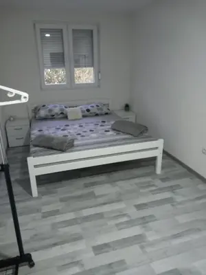 a bed in a white room with a window at Apartment B&E in Tuzla