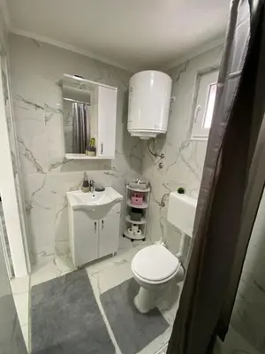 a white bathroom with a toilet and a sink at Apartment B&E in Tuzla