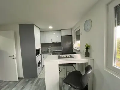 a kitchen with a table and a chair and a clock at Apartment B&E in Tuzla