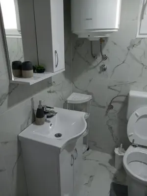 a white bathroom with a sink and a toilet at Apartment B&E in Tuzla
