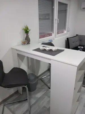 a white desk with a chair and two windows at Apartment B&E in Tuzla