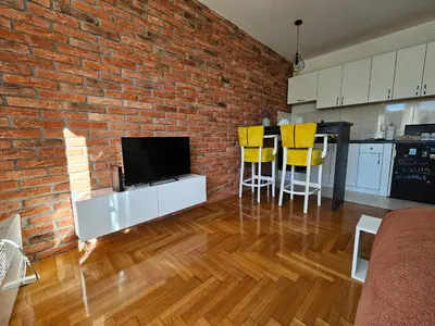 a living room with a brick wall and a flat screen tv at Apartman Lollita in Banja Luka