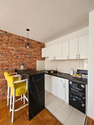 a kitchen with white cabinets and a brick wall at Apartman Lollita in Banja Luka
