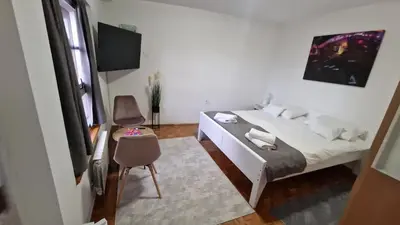 a bedroom with a bed and a desk and a chair at Olimpus Apartmani BD Banjaluka in Banja Luka