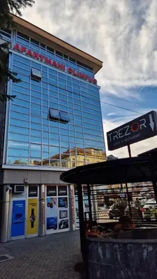 a large glass building with a sign in front of it at Olimpus Apartmani BD Banjaluka in Banja Luka
