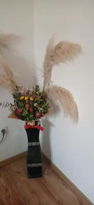 a vase filled with feathers and a bunch of flowers at Topli dom in Banja Luka
