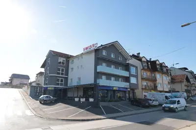 a building with cars parked in a parking lot at Swiss Apartmani in Banja Luka