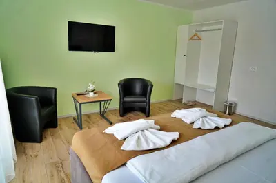 a bedroom with a bed with two chairs and a television at Swiss Apartmani in Banja Luka