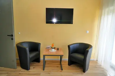 two chairs and a table with a television on a wall at Swiss Apartmani in Banja Luka