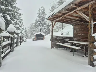 a log cabin in the snow with a car parked at VilaBellavistasmjestaj in Vlasic