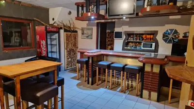 a restaurant with a bar with stools and a tv at VilaBellavistasmjestaj in Vlasic