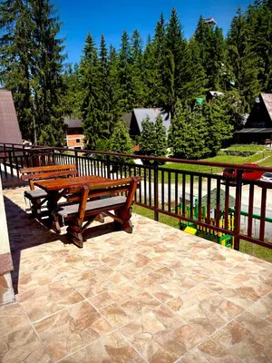 two wooden benches sitting on a patio next to a fence at Apartman RAJAN Vlašić in Vlasic