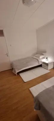 a white room with two beds and a table at Apartman Borik Banjaluka in Banja Luka