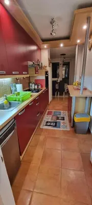 a kitchen with red cabinets and a tile floor at Apartman Borik Banjaluka in Banja Luka