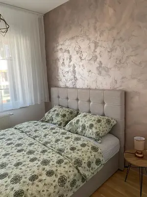 a bedroom with a bed with a floral blanket and pillows at Mona in Banja Luka