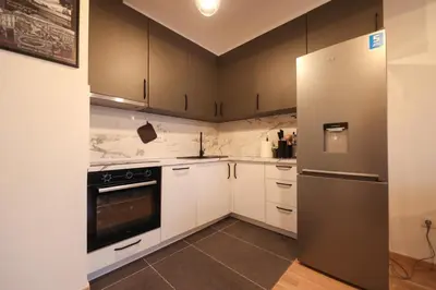 a kitchen with white cabinets and a stainless steel refrigerator at Apartman MRL Cavic in Banja Luka