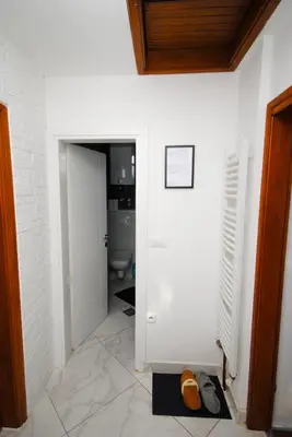 a hallway with a bathroom with a toilet and a door at Apartman Alchemist I in Bosanska Dubica