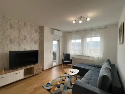 a living room with a blue couch and a flat screen tv at Apartman Vista Banja Luka in Banja Luka