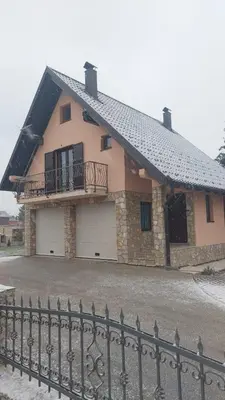 a house with two garage doors and a fence at Vikendica Mila in Kupres