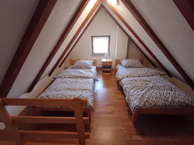 a attic room with three beds and a window at Vikendica Mila in Kupres