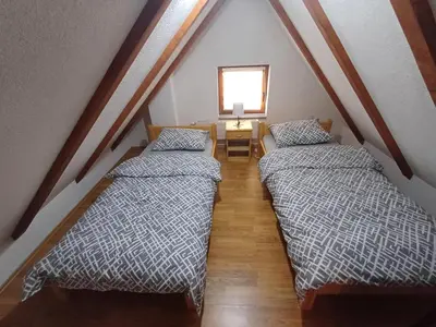 a attic room with two beds and a window at Vikendica Mila in Kupres