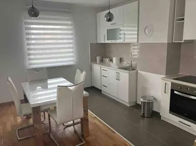 a kitchen with white cabinets and a table and chairs at Apartman Vrbas 1 + Podzemna garaza in Banja Luka
