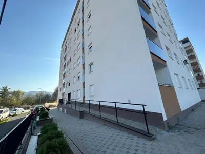 a white building with a ramp next to a street at Apartman Vrbas 1 + Podzemna garaza in Banja Luka