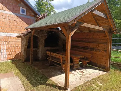 a wooden pavilion with a bench in front of a building at Vlašić, Babanovac, vikendica Ante in Vlasic