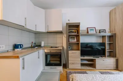 a kitchen with white cabinets and a flat screen tv at Studio Apartmani Donnie in Livno