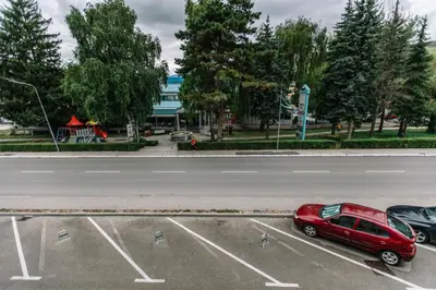 a red car parked in a parking lot next to a street at Studio Apartmani Donnie in Livno