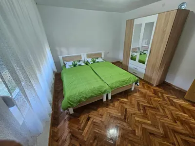 a bedroom with a green bed and a mirror at Apartman Capital Novi Grad in Bosanski Novi