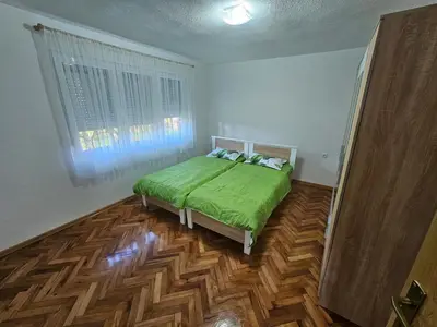 a bedroom with a green bed and a wooden floor at Apartman Capital Novi Grad in Bosanski Novi