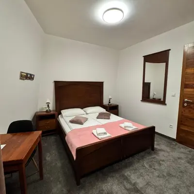 a bedroom with a bed and a table and a mirror at Hotel Paviljon in Bihać
