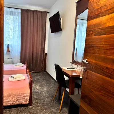 a room with two beds and a desk and a mirror at Hotel Paviljon in Bihać