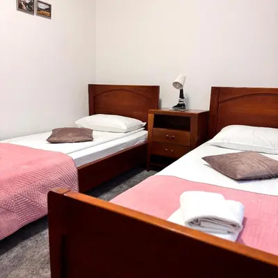 a room with two beds and a lamp on a table at Hotel Paviljon in Bihać