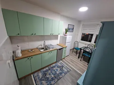 a kitchen with green cabinets and a dining room at Lilly Apartment Tuzla in Tuzla