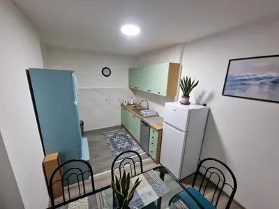 a small kitchen with a table and a refrigerator at Lilly Apartment Tuzla in Tuzla