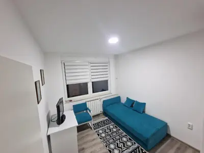 a living room with a blue couch and a window at Lilly Apartment Tuzla in Tuzla