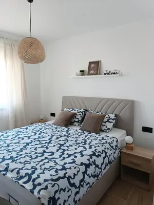 a bedroom with a bed with a blue and white comforter at Zen Apartment Tuzla in Tuzla