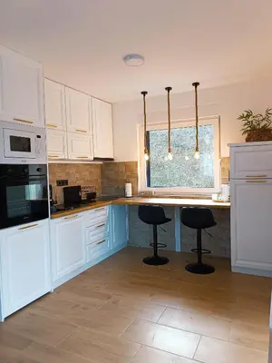 a kitchen with white cabinets and a counter with stools at Zen Apartment Tuzla in Tuzla