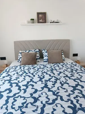 a bedroom with a bed with a blue and white comforter at Zen Apartment Tuzla in Tuzla