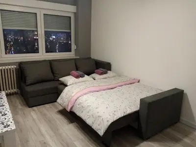 a bedroom with a bed and a couch and a window at Apartman Ćetojević in Banja Luka