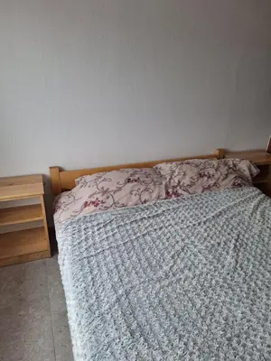 a bed with a blanket and a wooden head board at Apartmani 
