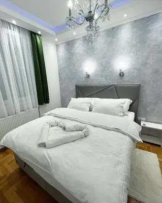 a bedroom with a large white bed with a chandelier at Apartman Central in Banja Luka