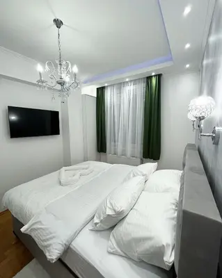 a bedroom with a large white bed and a chandelier at Apartman Central in Banja Luka