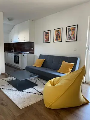 a living room with a blue couch and a kitchen at Apartman Dolly Bell in Kotor-Varoš