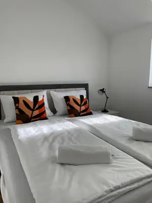 a large white bed with orange and black pillows at Apartman Dolly Bell in Kotor-Varoš