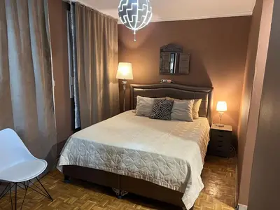 a bedroom with a bed and a chair and a chandelier at Banja Luka CITY2 in Banja Luka